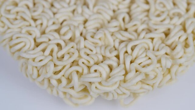 Highresolution image showing textured uncooked noodle cake surface. Close examination of fragile dried curly noodles arranged in tight coils on plain background