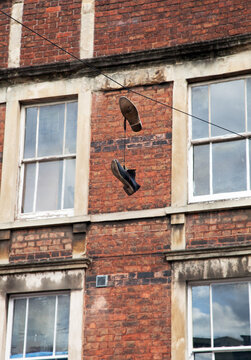 A pair of shoes hang from a power cable in front of a red brick building