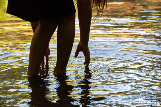 A young girl reaches to touch the water as she paddles