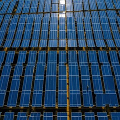 Aerial view of a large solar panel farm with rows of blue photovoltaic cells reflecting sunlight, representing renewable energy and sustainable power generation.
