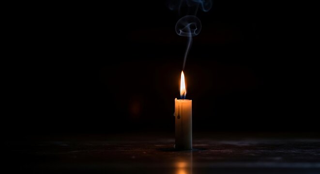 Candle burns brightly on table in dark room
