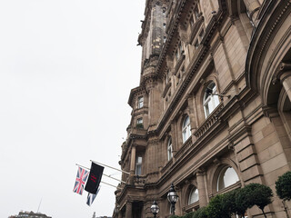 Obraz premium Historic sandstone building facade with Rocco Forte Hotels flags and ornate architecture in Edinburgh, Scotland, UK