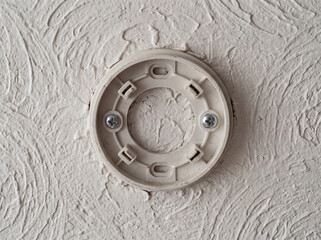 Obraz premium Smoke detector mounting bracket on textured ceiling. Close up.