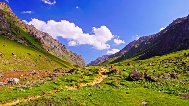 iron-oxidizing bacteria stream in mountain gorge at sunny summer day with blue sky and white clouds.
