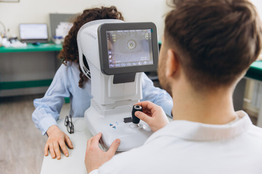 Optometrist conducting eye exam on a woman using an autorefractor, checking vision and eye health in a clinic