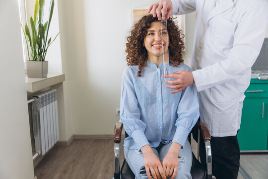 Optometrist measuring interpupillary distance for a smiling woman during an eye exam at a clinic