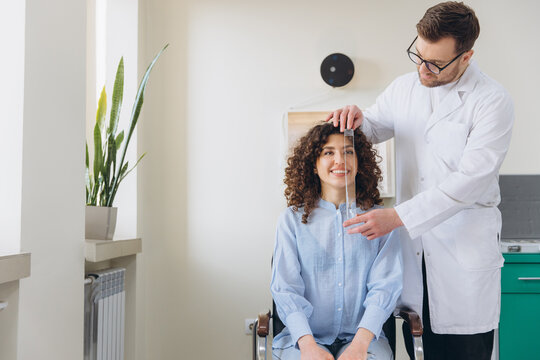 Optometrist measuring interpupillary distance for a woman getting new eyeglasses, undergoing a vision exam