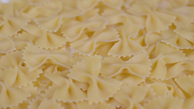 Closeup of golden bow pasta. Highresolution image of layered pale golden pasta pieces. Magnified view emphasizing scalloped edges and elegant textured patterns of pasta