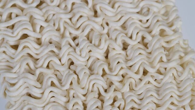 Pale beige dehydrated ramen with dense and wavy strands in close view. Highquality footage of crispy dried instant noodles with textured surface and intricate wave patterns