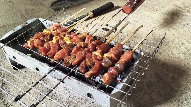 The process of grilling goat satay, a traditional Indonesian dish made from tender goat meat, over hot charcoal produces smoke and flames that enhance the flavor. Footage.