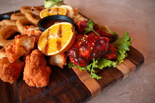 Imagen horizontal de un plato de alimentos fritos o aperitivos como aros de cebolla, alitas, boneless