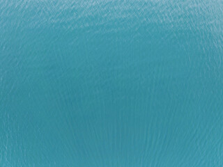 Stunning aerial top down view of vibrant turquoise sea water surface with organic ripple patterns, perfect for summer background. © Dmitri