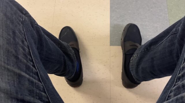 First person view of legs in jeans tapping foot rhythmically.