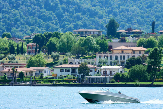 Panoramic view across Lake Iseo from Sarnico, located in Lombardy in Italy, towards the town of Paratico. The foreground features sparkling water and a speedboat