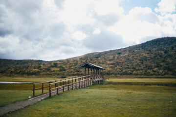 Fototapeta premium Wooden walkway leading to shelter over mountain wetland landscape