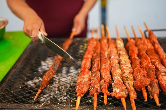 Latin woman entrepreneur grilling anticuchos at street food fair