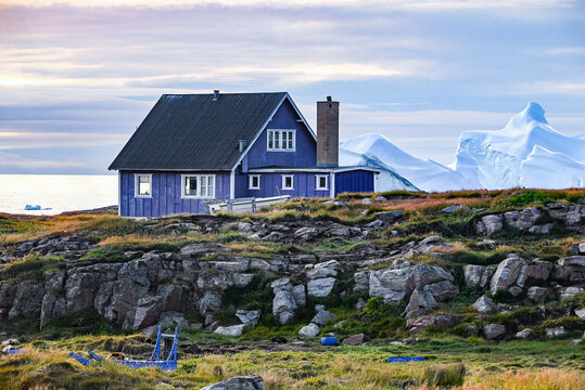 Qeqertarsuaq, Disko Island, Greenland - Colorful seascape with a charming blue cottage and icebergs