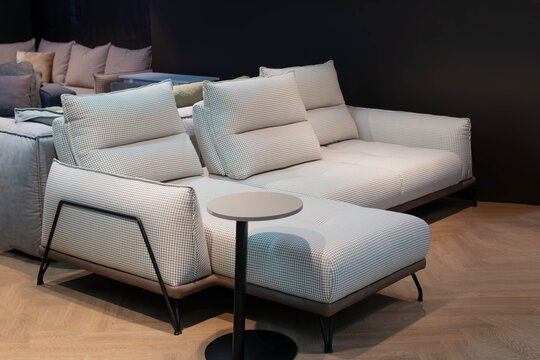Elegant modern sofa displayed in a spacious furniture showroom, featuring high-quality upholstery, stylish cushions, and a contemporary design for home comfort and interior inspiration