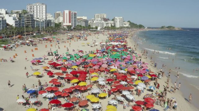 Aerial, drone shot of massive crowds on a sunny Ipanema beach in Rio de Janeiro