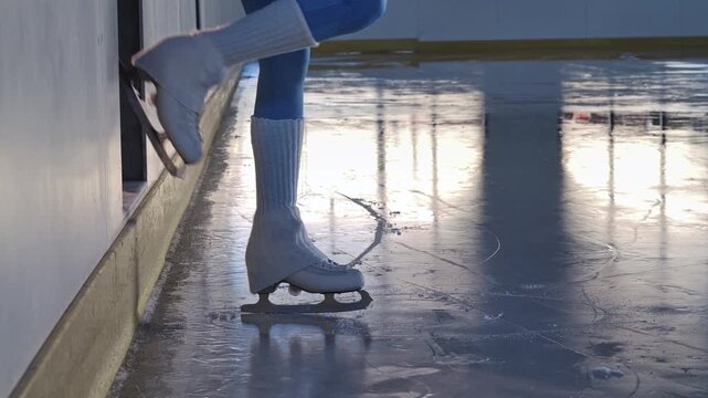 A close up of a figure skater legs begins training on a shiny indoor rink with reflections and shadows. An elegant winter sports scene demonstrating balance, movement, and training. Slow motion.