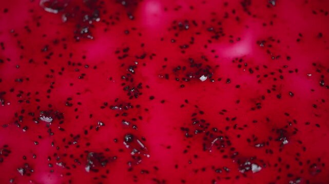 Closeup of shiny red jelly with seeds. Macro shot showing dark seeds in bright red preserve. Detailed image of viscous red currant jam with glossy finish and tiny seeds