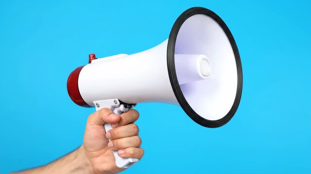 Male hand holding a megaphone for an important announcement or public alert. Communication, marketing and protest concept shown in a sequence with significant copy space