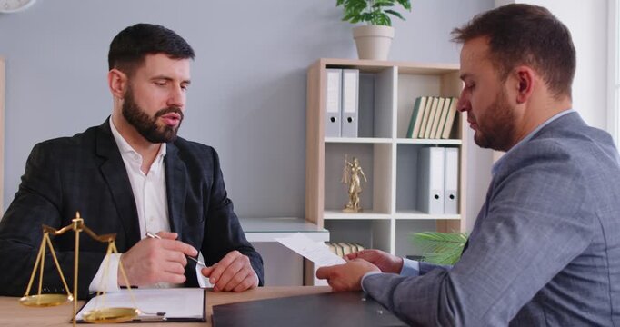 Lawyer legal consultation or contract terms discussion in office, scales of justice at desk, important conversation about legal matters, solicitor or barrister meeting, client listening attentively