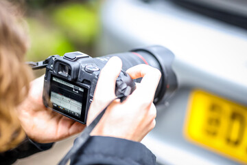 Young Photographer Capturing Luxury Car Detail on an Urban Street Scene