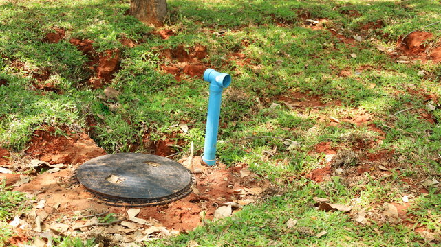 Septic tank with ventilation pipe. Black septic tank buried in the ground with blue ventilation pipe of toilet sanitation system with selective focus.