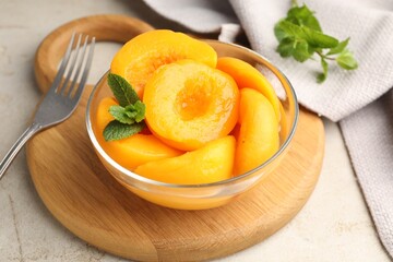 Pickled peaches and mint leaves in bowl on light grey table, closeup © New Africa