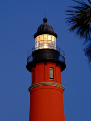 The Ponce Inlet Lighthouse beacon comes on in the early evening near the Atlantic Ocean