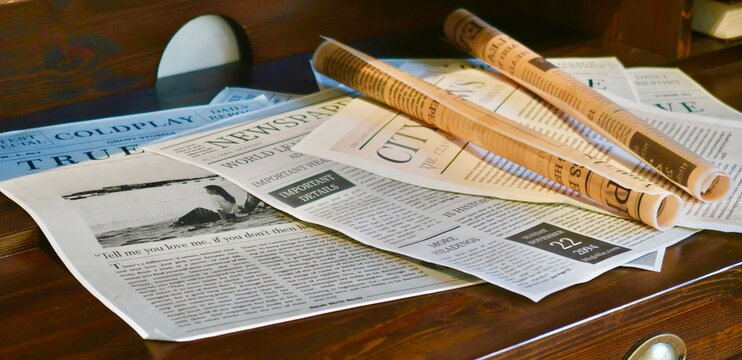 Stack of newspapers and eyeglasses on table