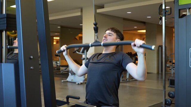 A close-up shot of a determined young man perform lat pulldowns at the gym. The mood is focused and energetic, show strength. Ideal for fitness, health, and exercise content
