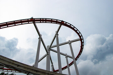 Structure modern steel roller coaster track in amusement park blue cloud sky is overcast is background. Thrilling roller coaster racing through twists and loops at lively excitement fun of high speed. © Thepporn