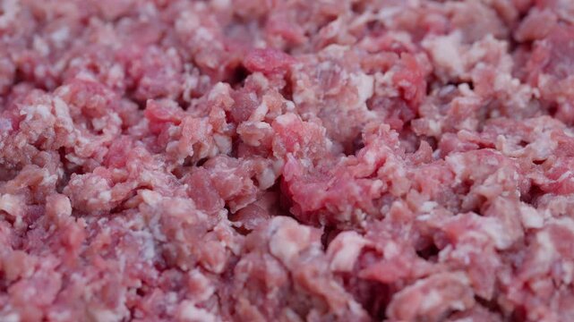 Closeup of raw ground beef texture, Highresolution shot of fresh raw beef preparation, Detailed footage showcasing raw minced beef with vibrant pink fat and lean strands