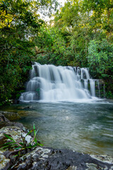 Obraz premium Lush forest environment showcasing a multi-tiered waterfall with silky smooth water cascading into a pristine pool, capturing the tranquility and raw beauty of unspoiled nature
