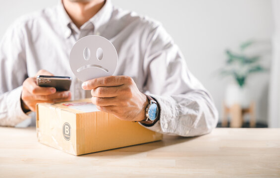 Dissatisfaction with online shopping experience, customer provides service feedback holding sad face emoji and mobile phone, highlighting poor delivery box and negative customer experience