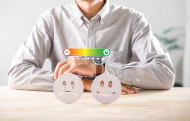 Contrast of happy sad emotional faces shows customer satisfaction survey, mapping mood health improvement from unhappy states, with person observing progress bar on wooden table
