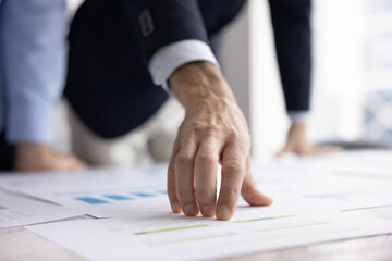 Obraz premium Data point focus. Cropped close up businessman hand in formal suit show statistic detail on paper project on table. Financial report analysis business infographics review benchmarking planning concept