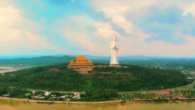 Full 4K aerial push-in to the hilltop Minh Duc Pagoda, capturing the temple complex and giant statue surrounded by the lush natural landscape.