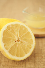 Lemon cut in half on wooden table with lemon juice nearby