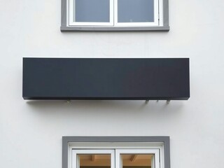 Fototapeta premium A black object mounted on a wall between two windows