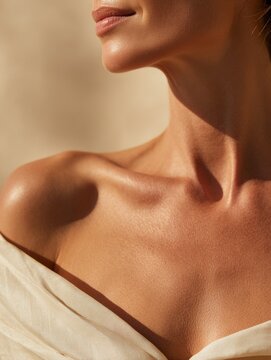 Skincare and beauty branding &ndash; close-up of woman neck and collarbone with sun-kissed glowing skin, minimal warm background