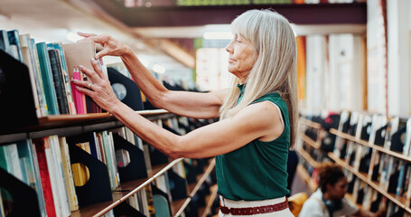 Librarian, woman and pack books on bookshelf for stock control, sort returns or organize material. Mature person, employee or check resources in library for inventory, reshelving or novel arrangement © peopleimages.com