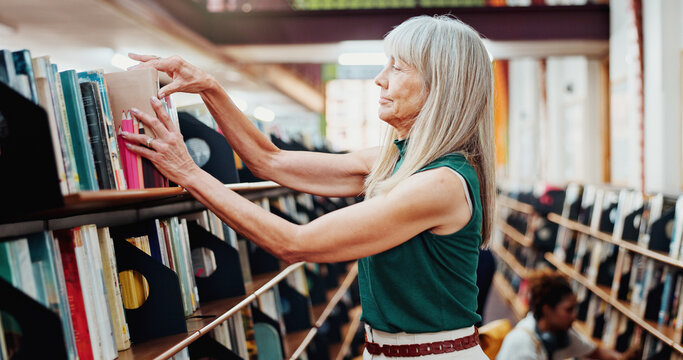 Librarian, woman and pack books on bookshelf for stock control, sort returns or organize material. Mature person, employee or check resources in library for inventory, reshelving or novel arrangement