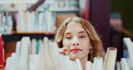 Fototapeta premium Student, girl and search on bookshelf at college for book choice, pick textbook and knowledge. University, person and check course resources in library for study research, thesis citation or learning