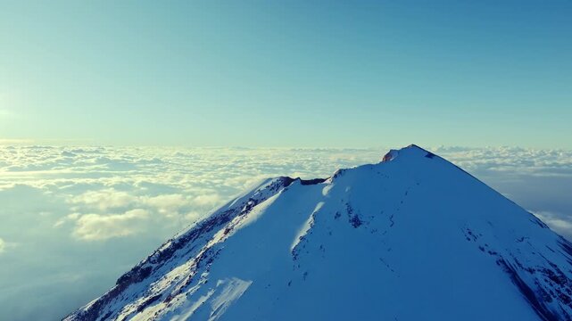 4K aerial drone view of the snow covered summit of Pico de Orizaba, also known as Citlaltepetl, the highest volcano in Mexico. Dramatic volcanic peak rising above a sea of clouds.