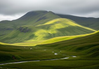 Fototapeta premium Green valley with winding river and sunlit hills