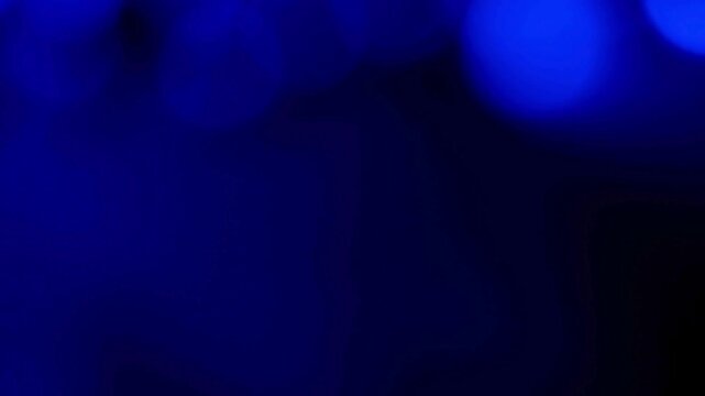Blue light leaks create a soft abstract texture with glowing circular bokeh effects on a dark background.