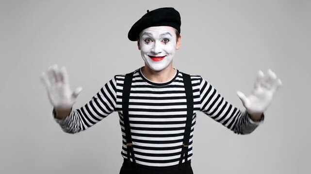 Mime artist in costume with raised hands in studio